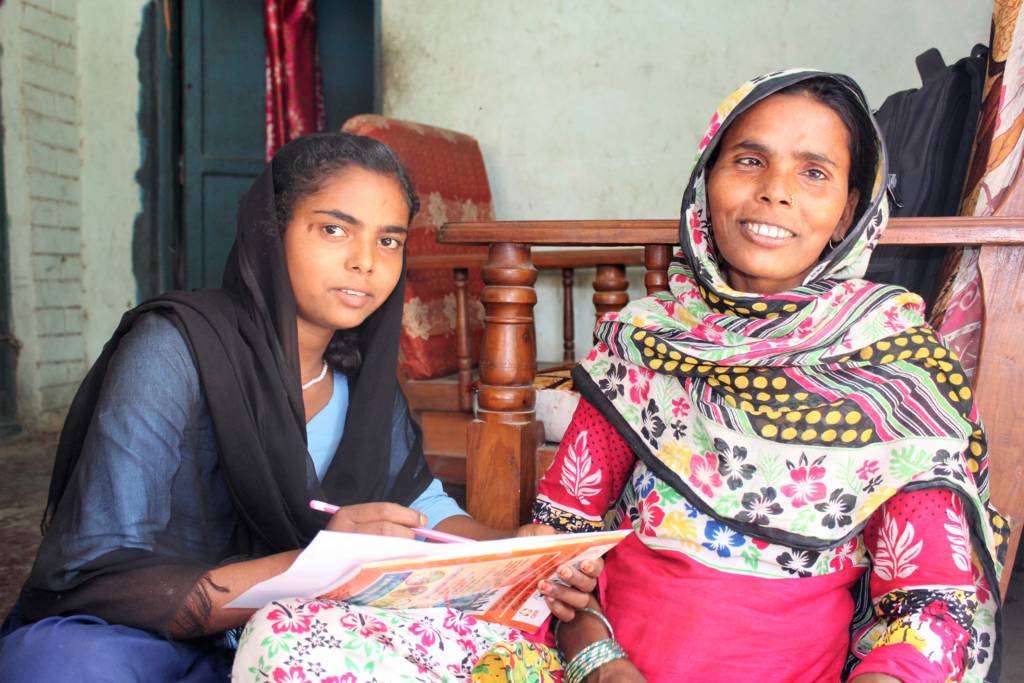 Afshana  and her mother Amirun.  Afshana was one of the many girls who had dropped out of school early due to the popular belief in her community that girls should stay at home. However, after attending various interaction / orientation meetings with CARE Nepal, Amirun is now aware of the importance of her daughter's education. Afsana is now a UDAAN Learning Center graduate.  Here, Afshana teaches her mother how to write her own name.  Photo: Care Austria